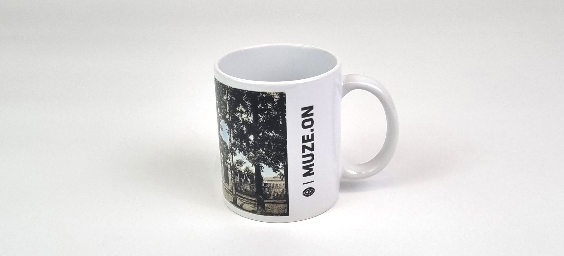 Kubek ceramiczny z pocztówką Muzeum Miejskiego w Żorach.